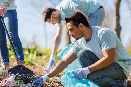 volunteers with garbage bags cleaning area in park